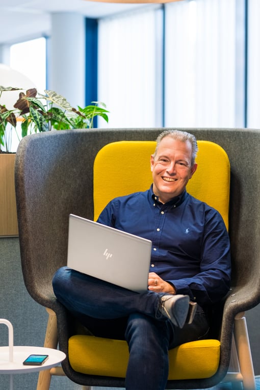 Han Strijbos from HEYDAY laughing at the camera while sitting on a remote workstation