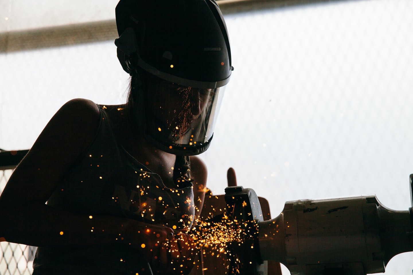 Someone who is grinding metal in a manufacturing factory