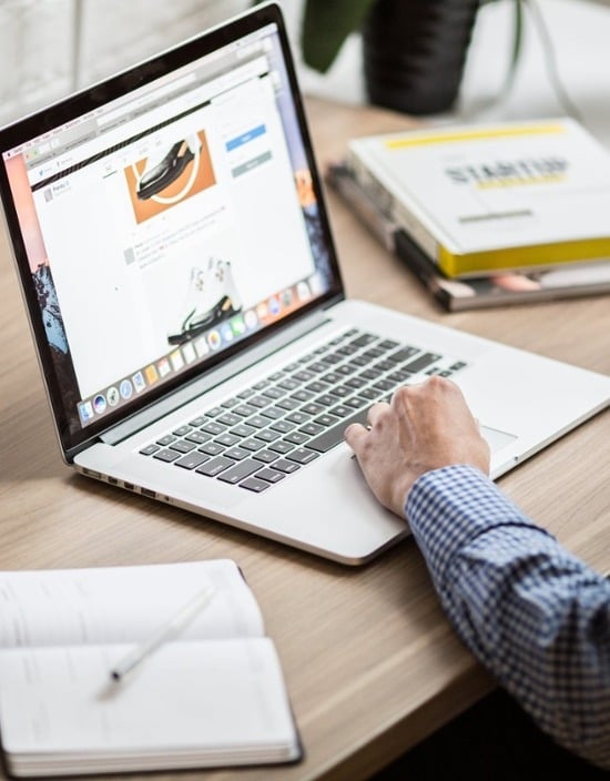 Person working on his laptop while keeping track of his notes